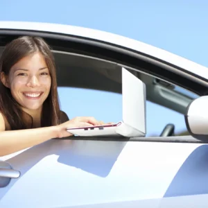 Smiling woman using laptop from car window
