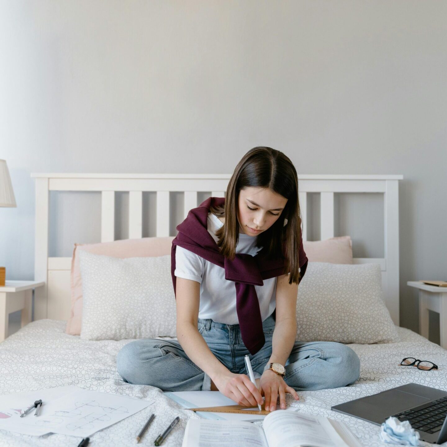 Young woman studying on bed with laptop